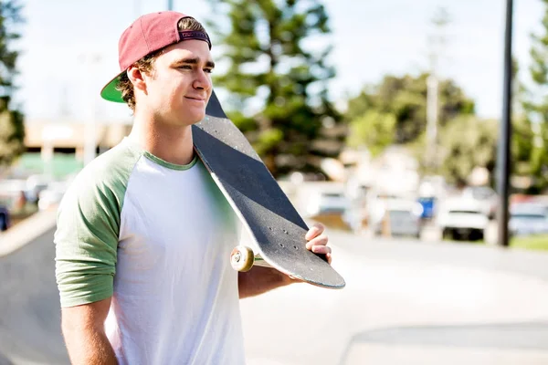 Мальчик-подросток со скейтбордом стоит на улице — стоковое фото