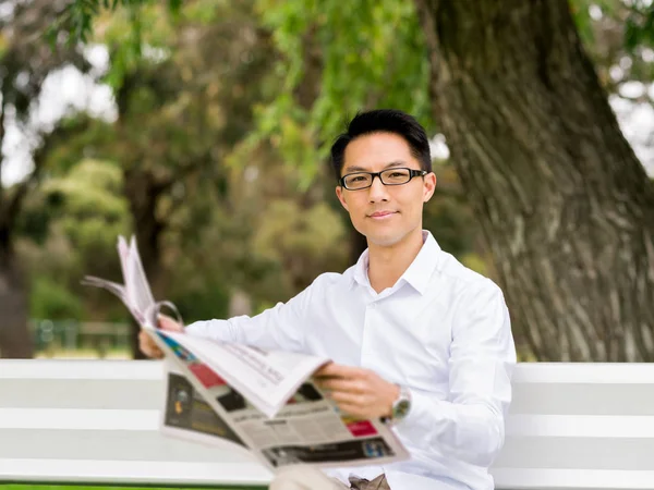 İş adamı parkta bir gazete okuyor