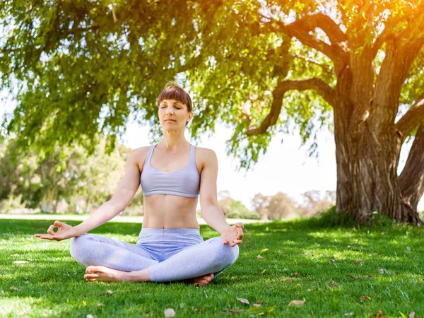 Jonge vrouw het beoefenen van yoga in het park — Stockfoto