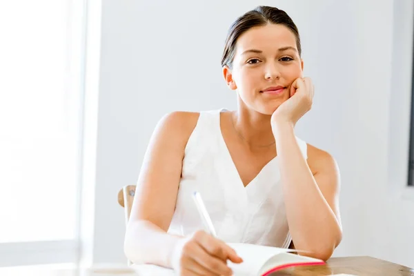 Jeune femme écrivant dans un agenda à la maison ou au bureau — Photo