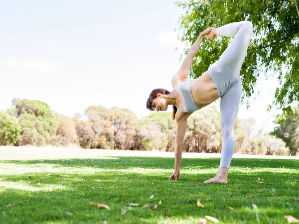 Giovane donna che pratica yoga nel parco — Foto Stock