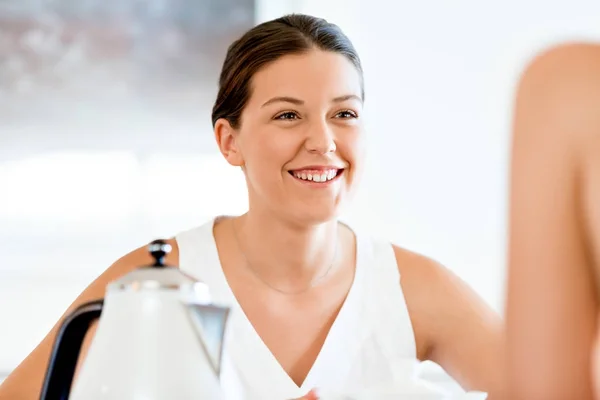 Молода жінка з подругою сидить за столом — стокове фото