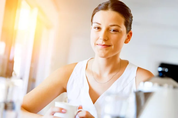 Mujer joven feliz con taza de té o café en casa — Foto de Stock