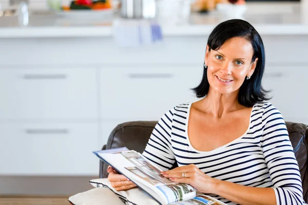 Heureuse femme lisant un livre assis sur un canapé — Photo