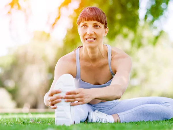 Parkta egzersiz yapan genç bir kadın.