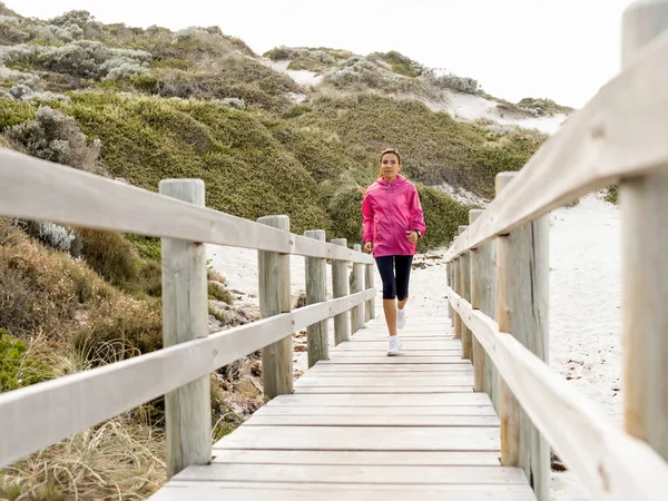 Mladá žena jogging na pláži — Stock fotografie