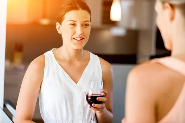 Giovane donna con la sua amica che tiene un bicchiere di vino in casa — Foto Stock