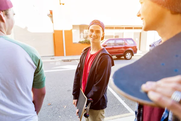 Tonåring pojke walking på gatan med sin skateboard — Stockfoto