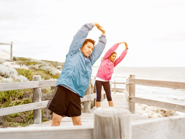 Jeune couple au bord de la mer faisant des exercices — Photo