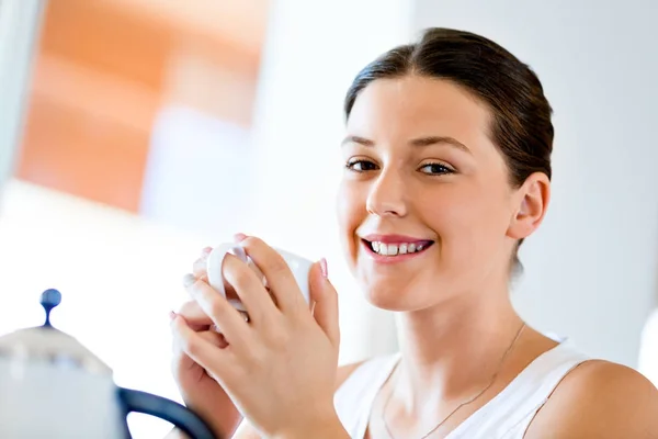 Щаслива молода жінка з чашкою чаю або кави вдома — стокове фото