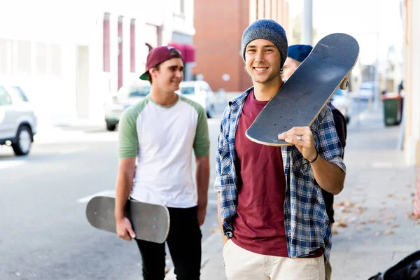 Adolescente niño caminando por la calle con su monopatín — Foto de Stock