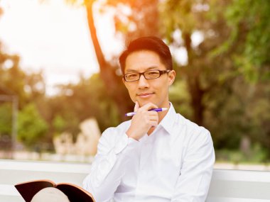 Bankta oturan ve Not Defteri'nde yazma çekici düşünceli işadamı