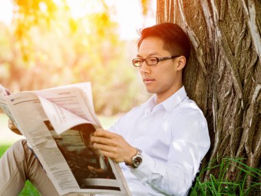 İş adamı parkta bir gazete okuyor
