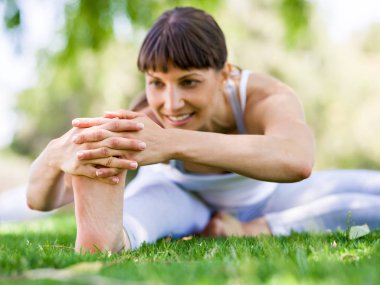 Genç kadın parkta yoga yapıyor.