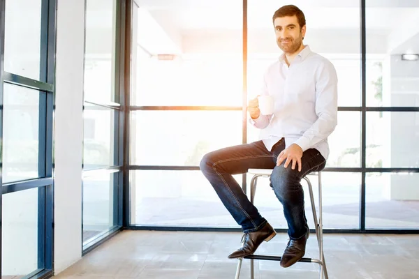 Jeune homme d'affaires assis sur un tabouret au bureau — Photo