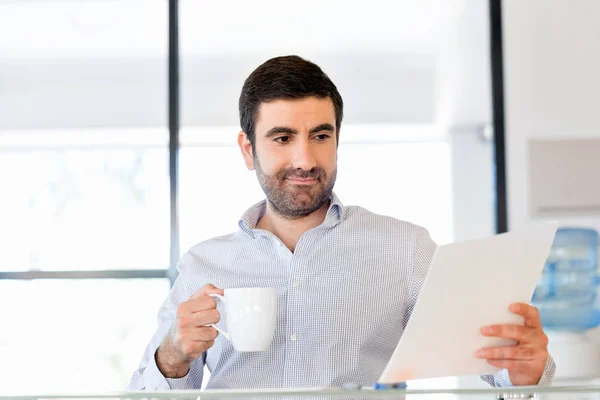 Handsome young man holding paper in office — Stock Photo, Image
