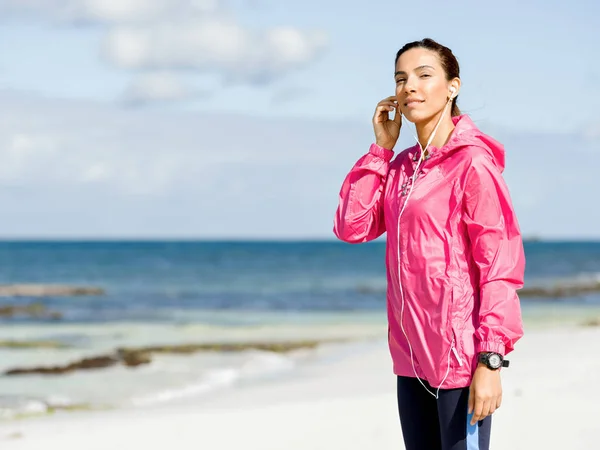 Sportieve vrouw met koptelefoon aan de kust van de zee — Stockfoto