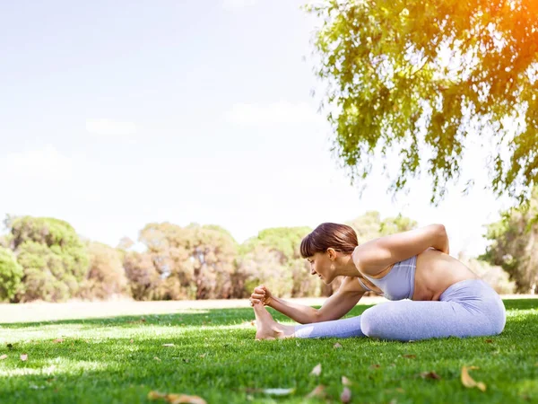 Jonge vrouw het beoefenen van yoga in het park — Stockfoto