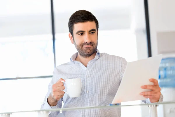 Knappe jonge man houden van papier in kantoor — Stockfoto