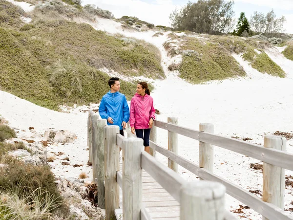 Νεαρός άνδρας και γυναίκα σε αθλητικά ενδύματα που περπατούν στην παραλία — Φωτογραφία Αρχείου