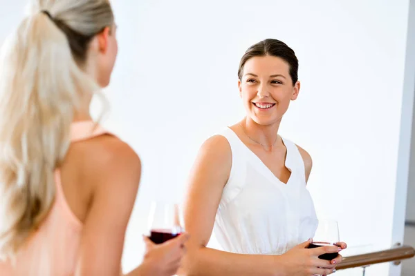 Ung kvinna med hennes vän hålla ett glas vin inomhus — Stockfoto