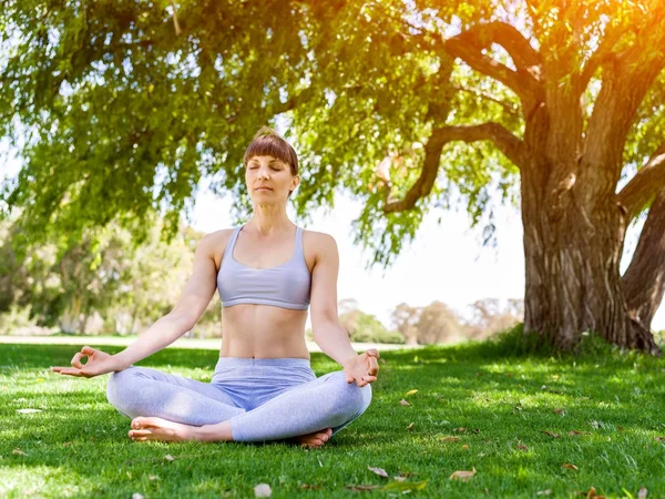 Genç kadın parkta yoga yapıyor. — Stok fotoğraf