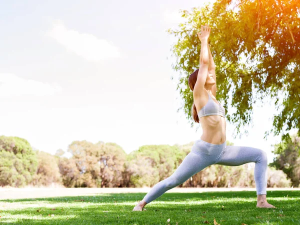 Jeune femme pratiquant le yoga dans le parc — Photo