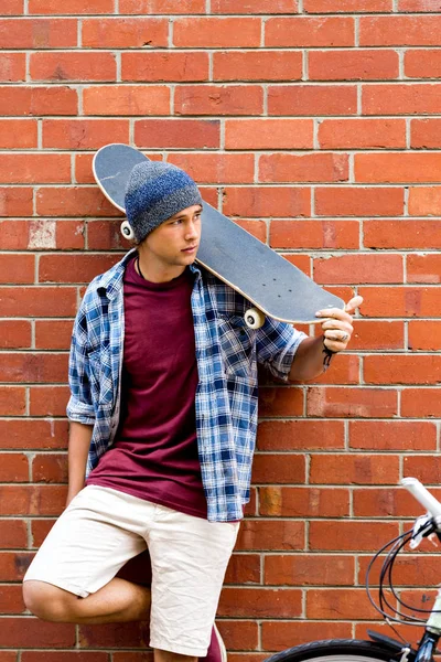 Duvarın yanında durduğunu kaykay ile genç çocuk