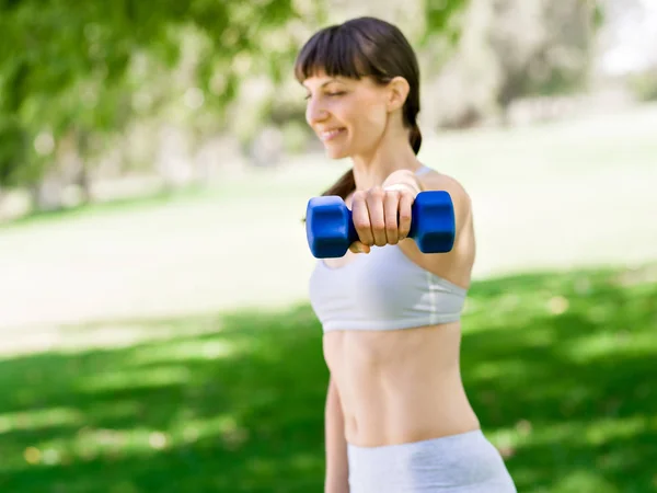 Porträt einer fröhlichen Frau in Fitnessbekleidung, die mit einer Hantel trainiert — Stockfoto