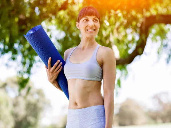 Young woman witth a gym mat in the park — Stock Photo, Image