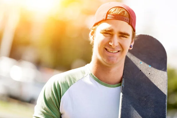 Adolescente com skate de pé ao ar livre — Fotografia de Stock