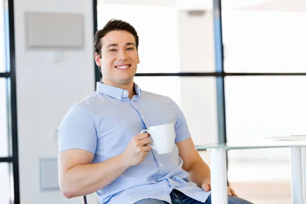 Young businessman in office with a mug — Stock Photo, Image