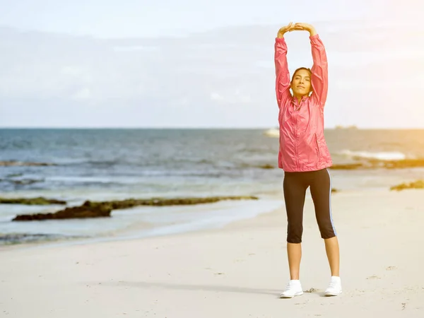 Молодая женщина на пляже делает упражнения — стоковое фото