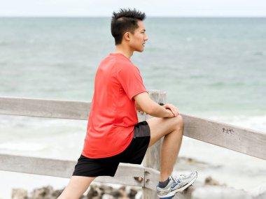 Genç adam sahilde egzersiz yaparak