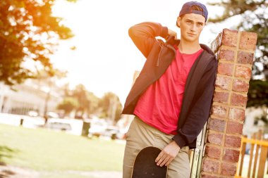 Duvarın yanında durduğunu kaykay ile genç çocuk