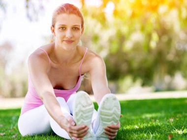 Parkta egzersiz yapan genç bir kadın.