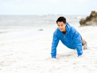 Genç adam sahilde egzersiz yaparak