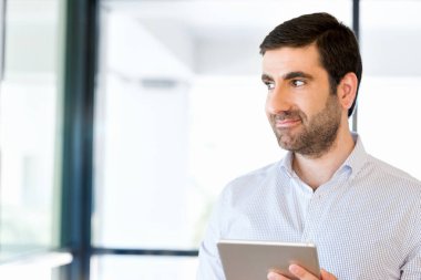 Genç yakışıklı işadamı onun touchpad ayakta kullanma office