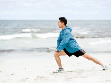 Genç adam sahilde egzersiz yaparak