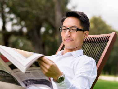 İş adamı parkta bir gazete okuyor