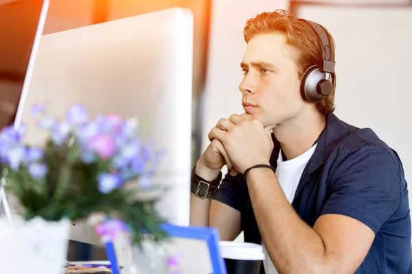 Jeune homme dans le bureau avec écouteurs — Photo