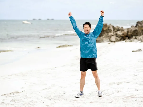 Jonge man met uitgestoken armen op het strand — Stockfoto