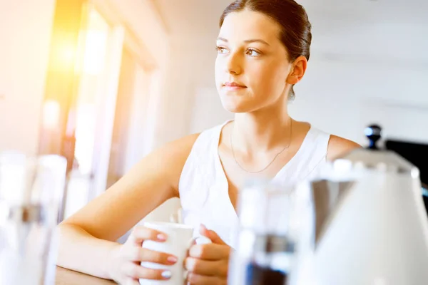 Glückliche junge Frau mit einer Tasse Tee oder Kaffee zu Hause — Stockfoto