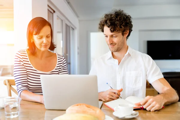 Gelukkige moderne paar bezig met laptop thuis — Stockfoto