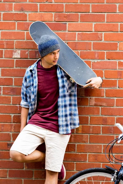 Εφηβικό αγόρι με skateboard στέκεται δίπλα στον τοίχο — Φωτογραφία Αρχείου