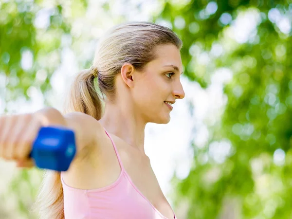 Porträt einer fröhlichen Frau in Fitnessbekleidung, die mit einer Hantel trainiert — Stockfoto