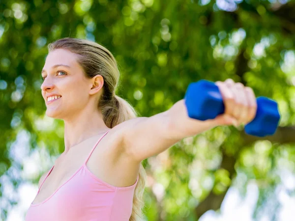 Portrait of cheerful woman in fitness wear exercising with dumbbell — Stock Photo, Image