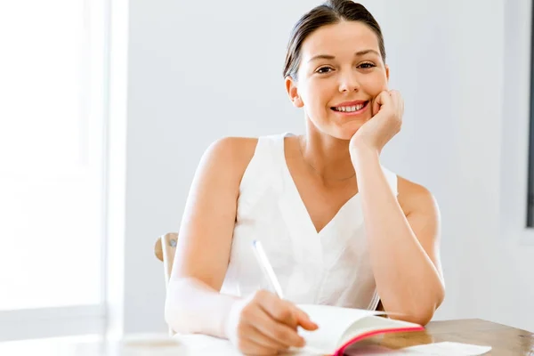 Jonge vrouw schrijven een agenda thuis of op kantoor — Stockfoto