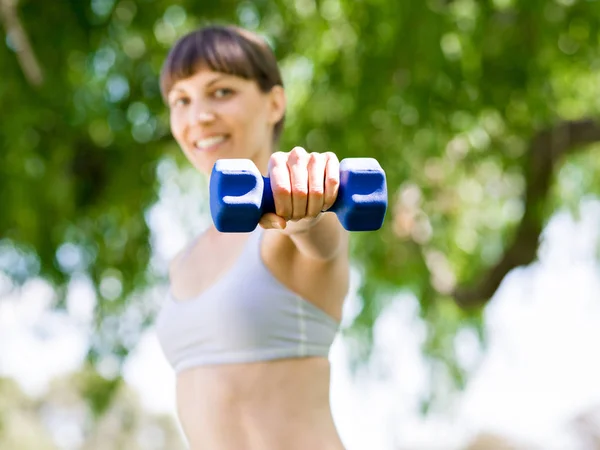 Porträt einer fröhlichen Frau in Fitnessbekleidung, die mit einer Hantel trainiert — Stockfoto