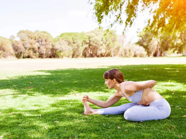 Genç kadın parkta yoga yapıyor. — Stok fotoğraf